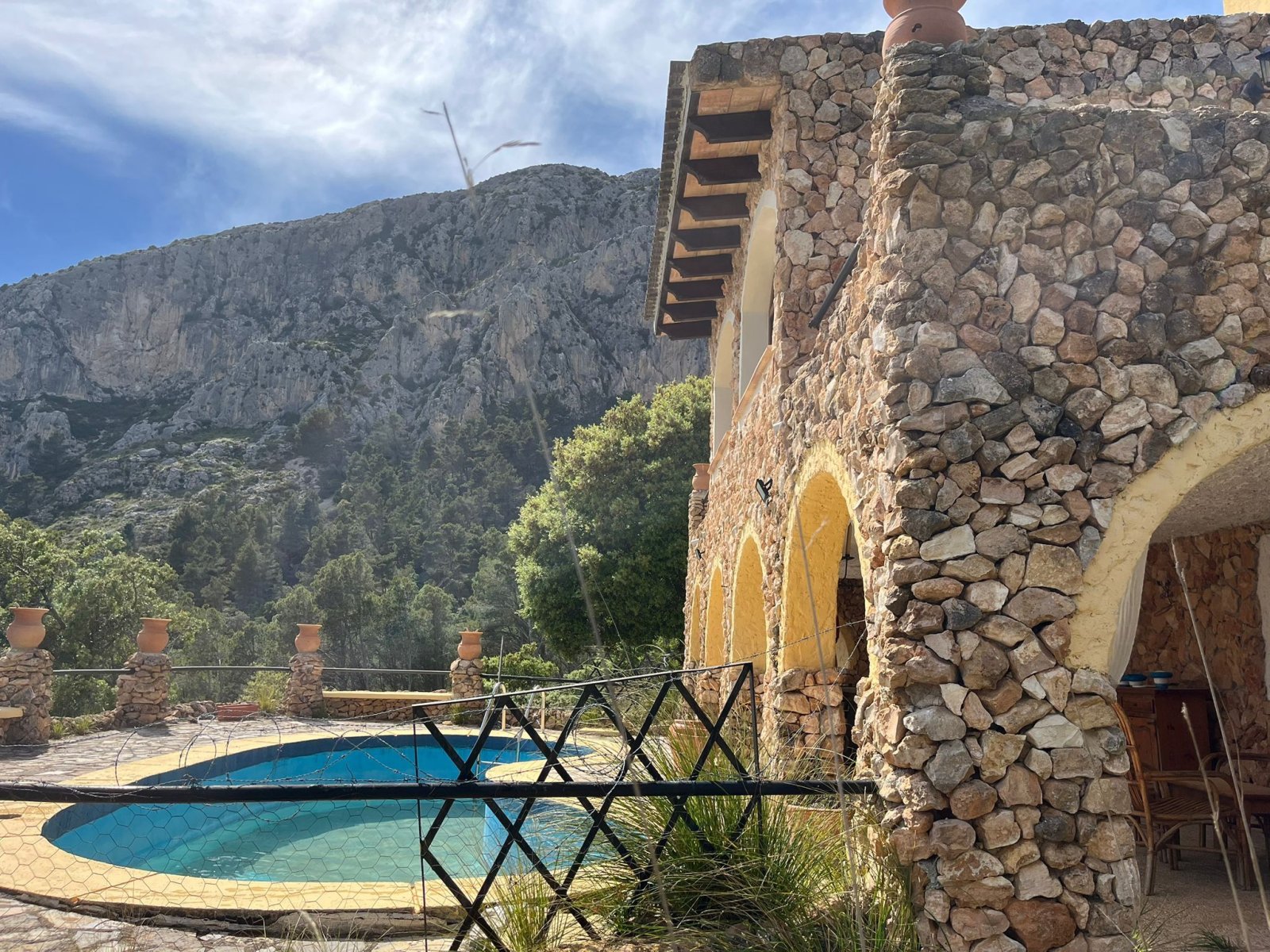 Covered pool terrace with solid natural stone arches – shaded area with rustic character and mountain panorama