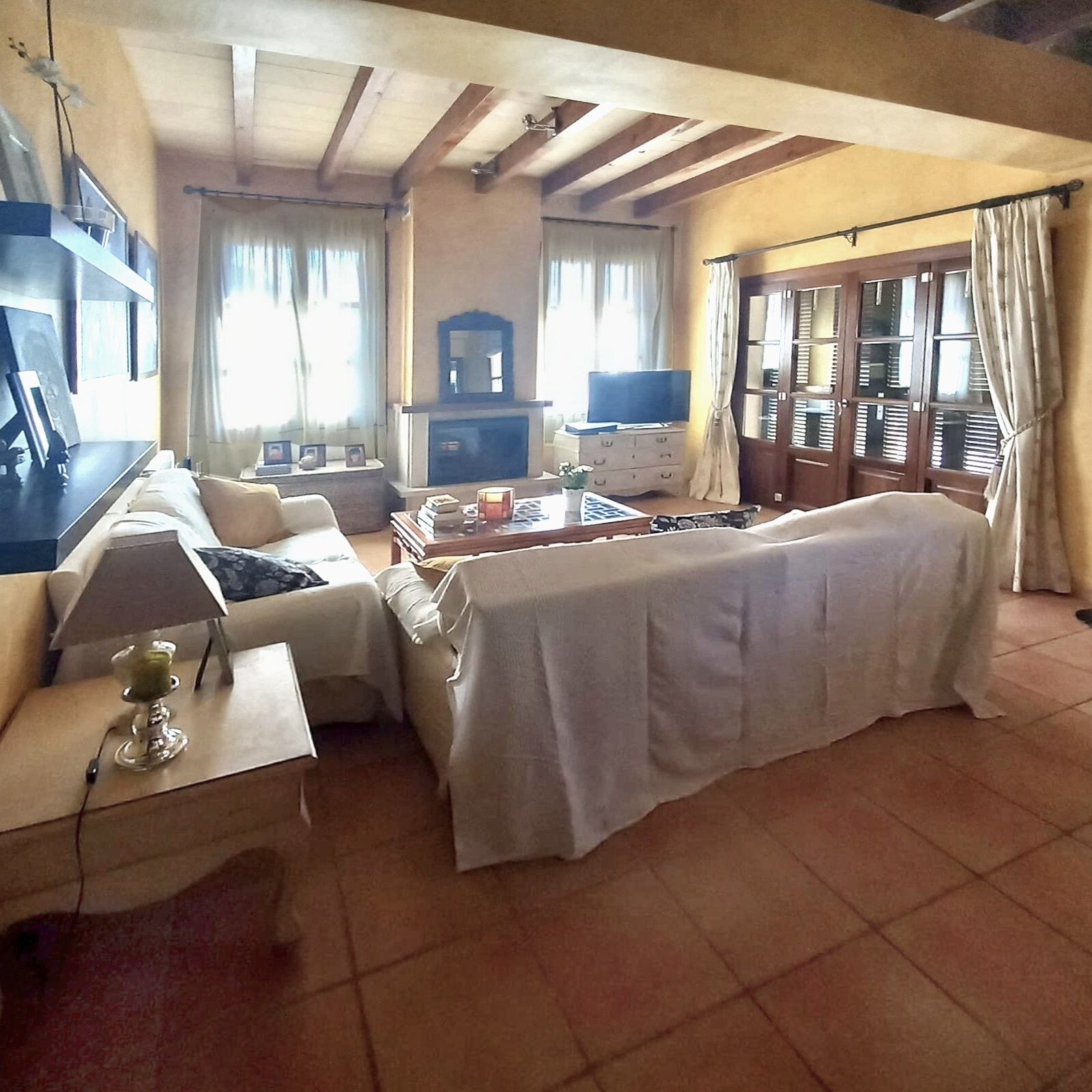 Living/sleeping area with exposed beam ceiling and large glass sliding doors to the outdoor area