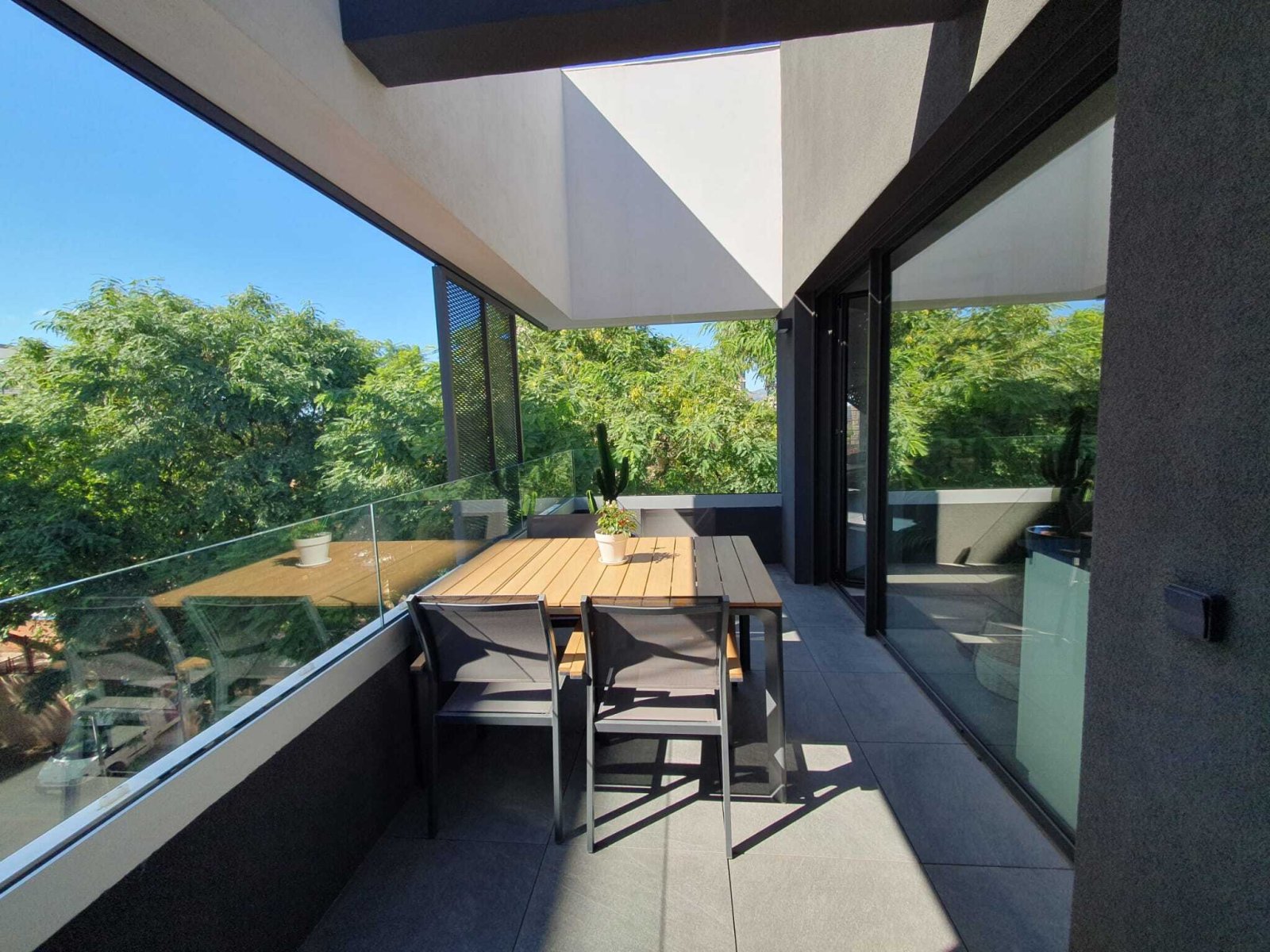 Modern terrace with thoughtful sun protection and floor-to-ceiling glass sliding doors to the living area