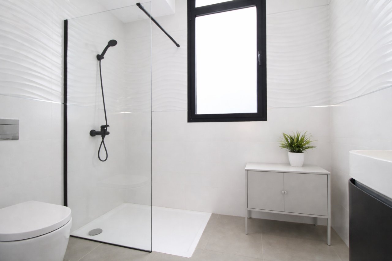 Modern bathroom with walk-in shower, glass partition, and skylight window