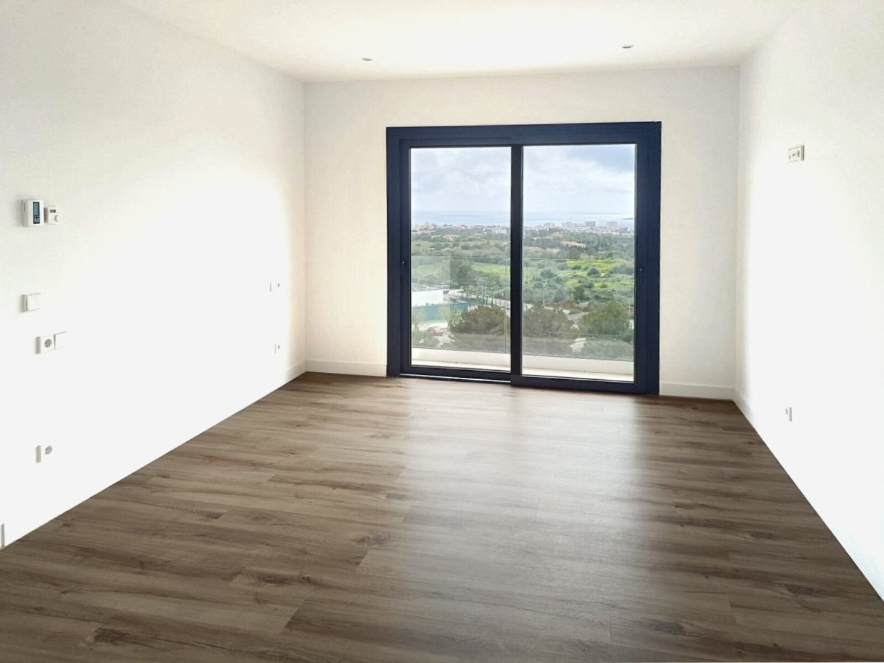 Bright corner room with floor-to-ceiling sliding doors and a distant view of the landscape Bright corner room with floor-to-ceiling sliding doors and a distant view of the landscape