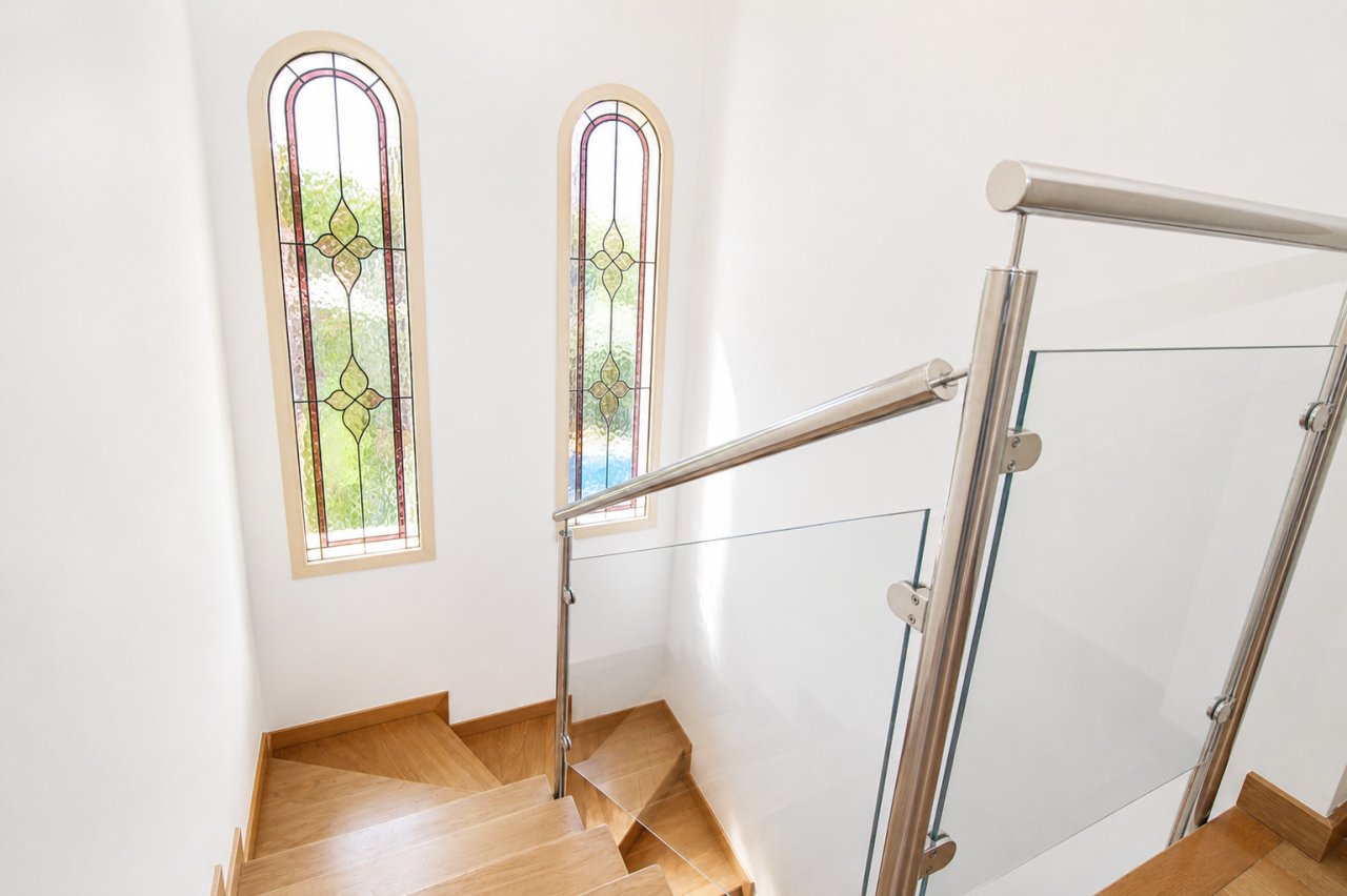 Elegant staircase hall with distinctive stained glass windows and modern stainless steel railing Elegant staircase hall with distinctive stained glass windows and modern stainless steel railing