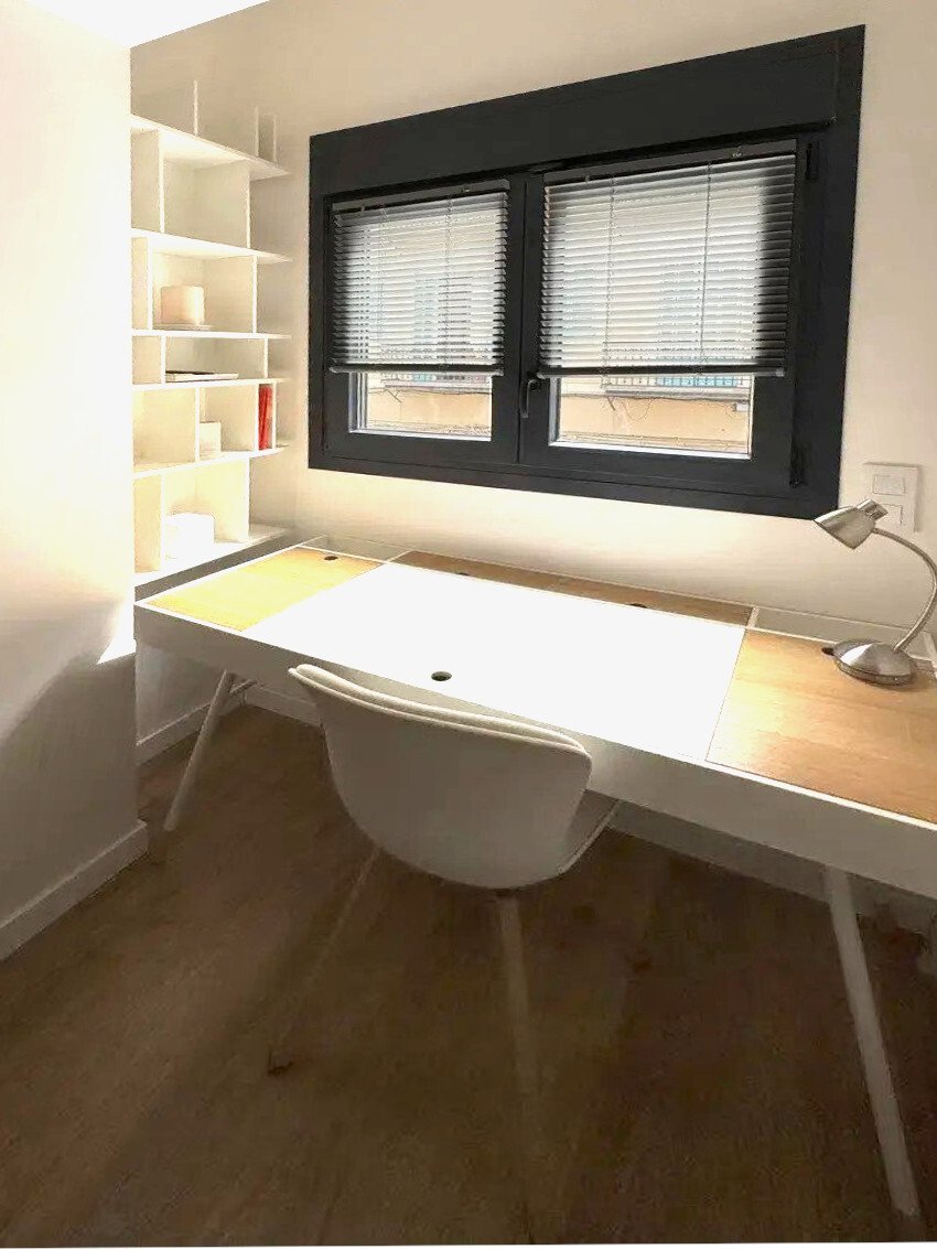 Home office with integrated shelving wall system and large windows Home office with integrated shelving wall system and large windows