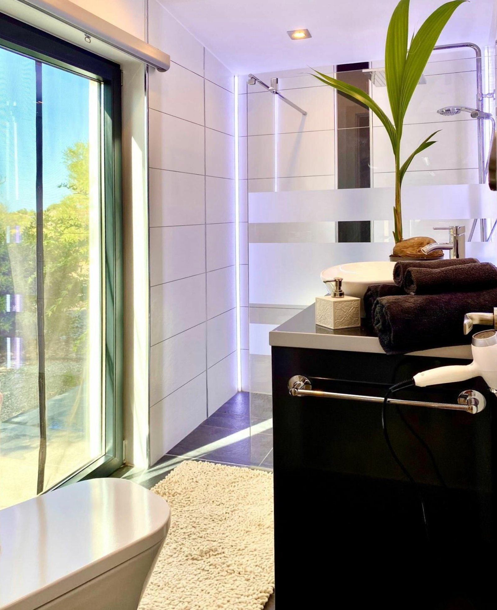 Modern bathroom with walk-in shower, double sink vanity, and large mirror front with LED lighting