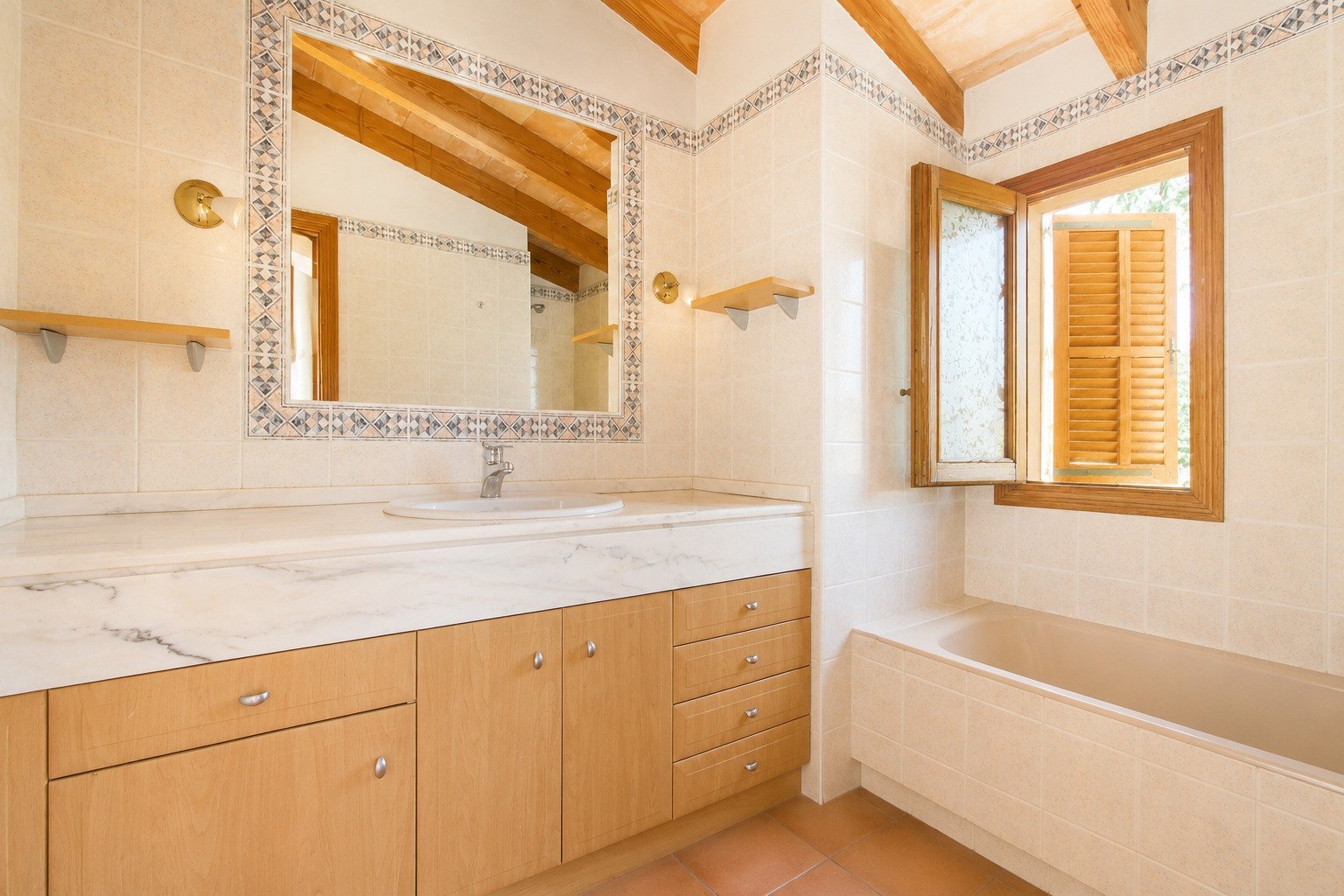 Bathroom with marble sink, decorative mirror frame, and bathtub with window view Bathroom with marble sink, decorative mirror frame, and bathtub with window view