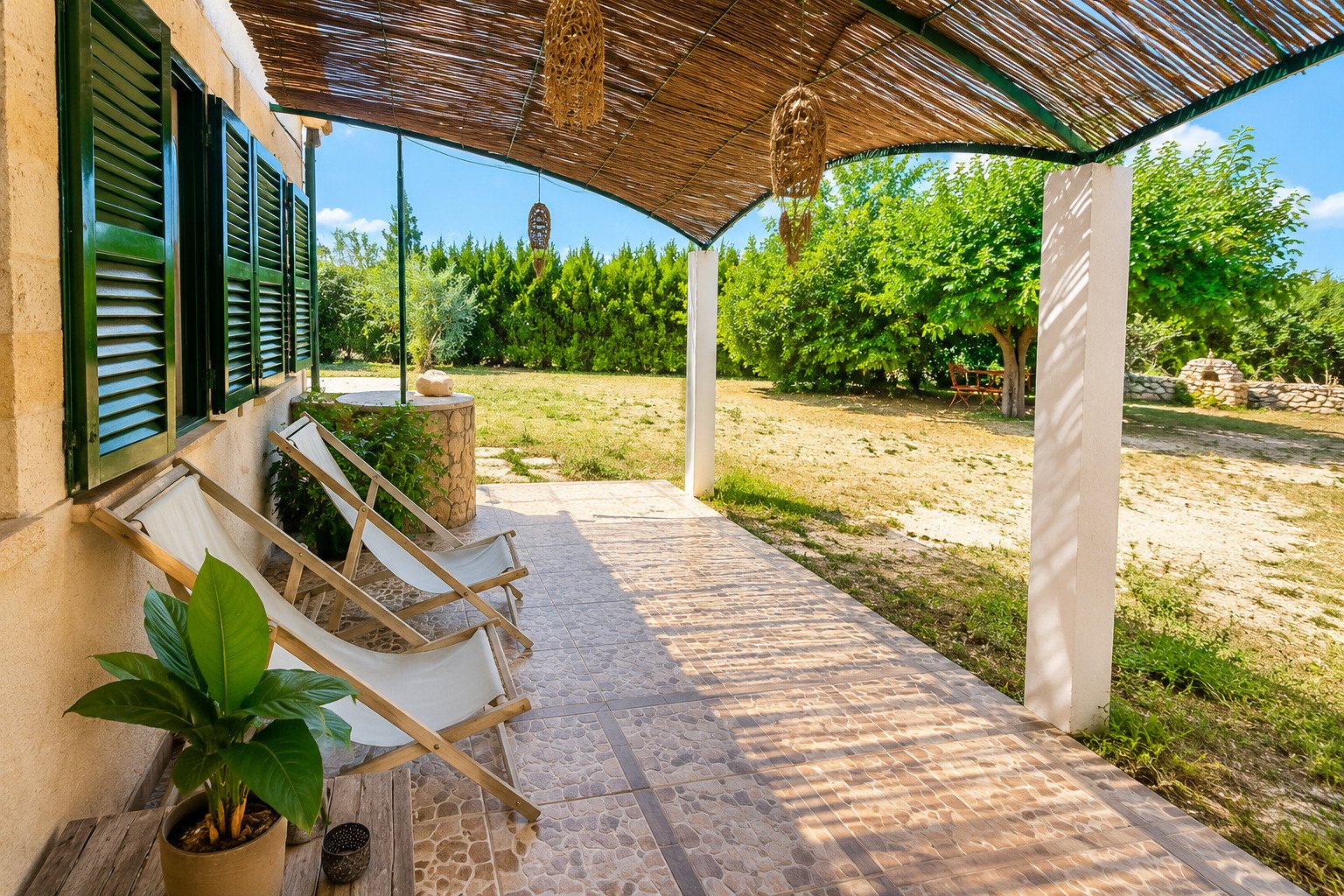 Covered terrace with natural stone flooring and views of the spacious property