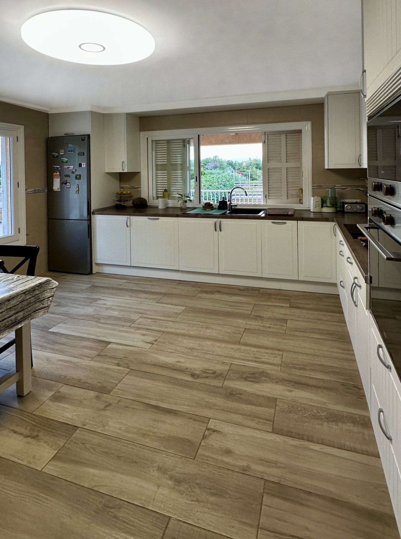 Modern kitchen with ample workspace and panoramic window to the greenery
