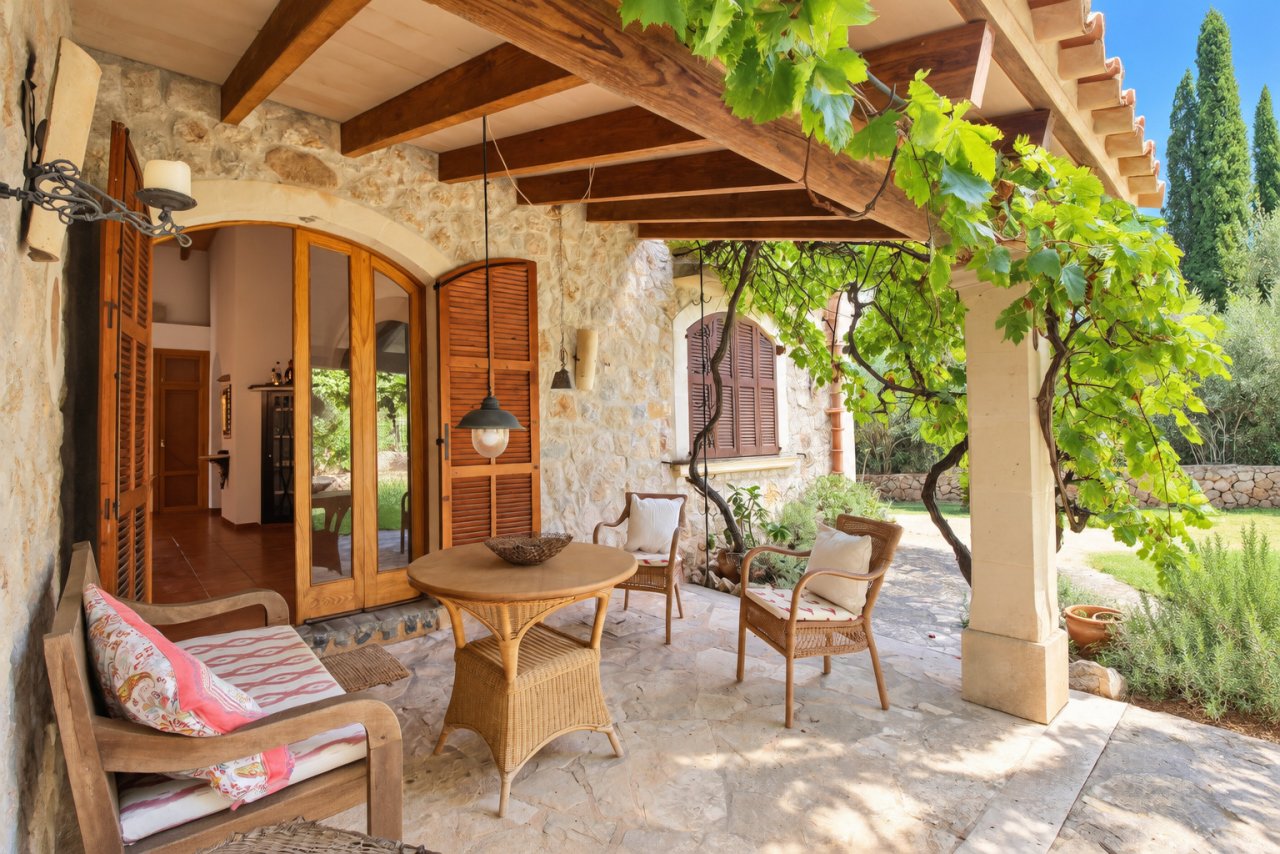 Covered veranda with wooden beam ceiling, natural stone walls, and seamless transition to the garden Covered veranda with wooden beam ceiling, natural stone walls, and seamless transition to the garden