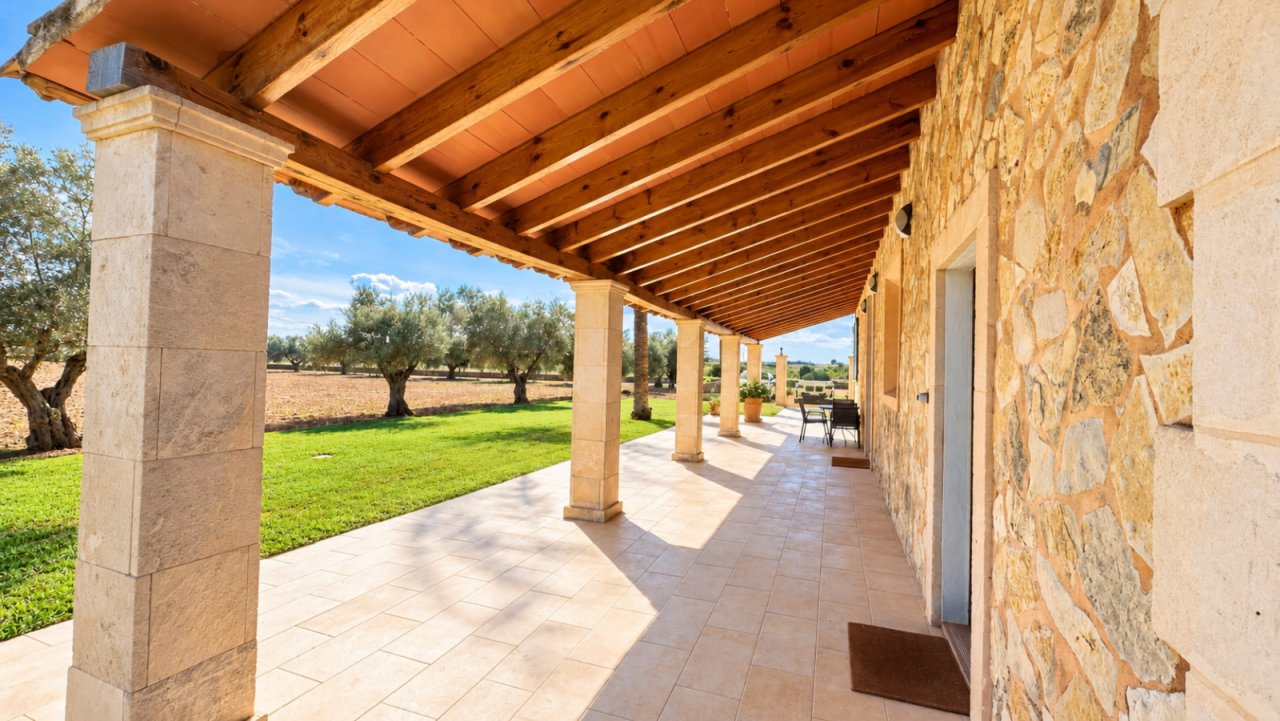 Veranda with rustic stone facade and shaded wooden overhang, ideal for relaxing outdoor hours.