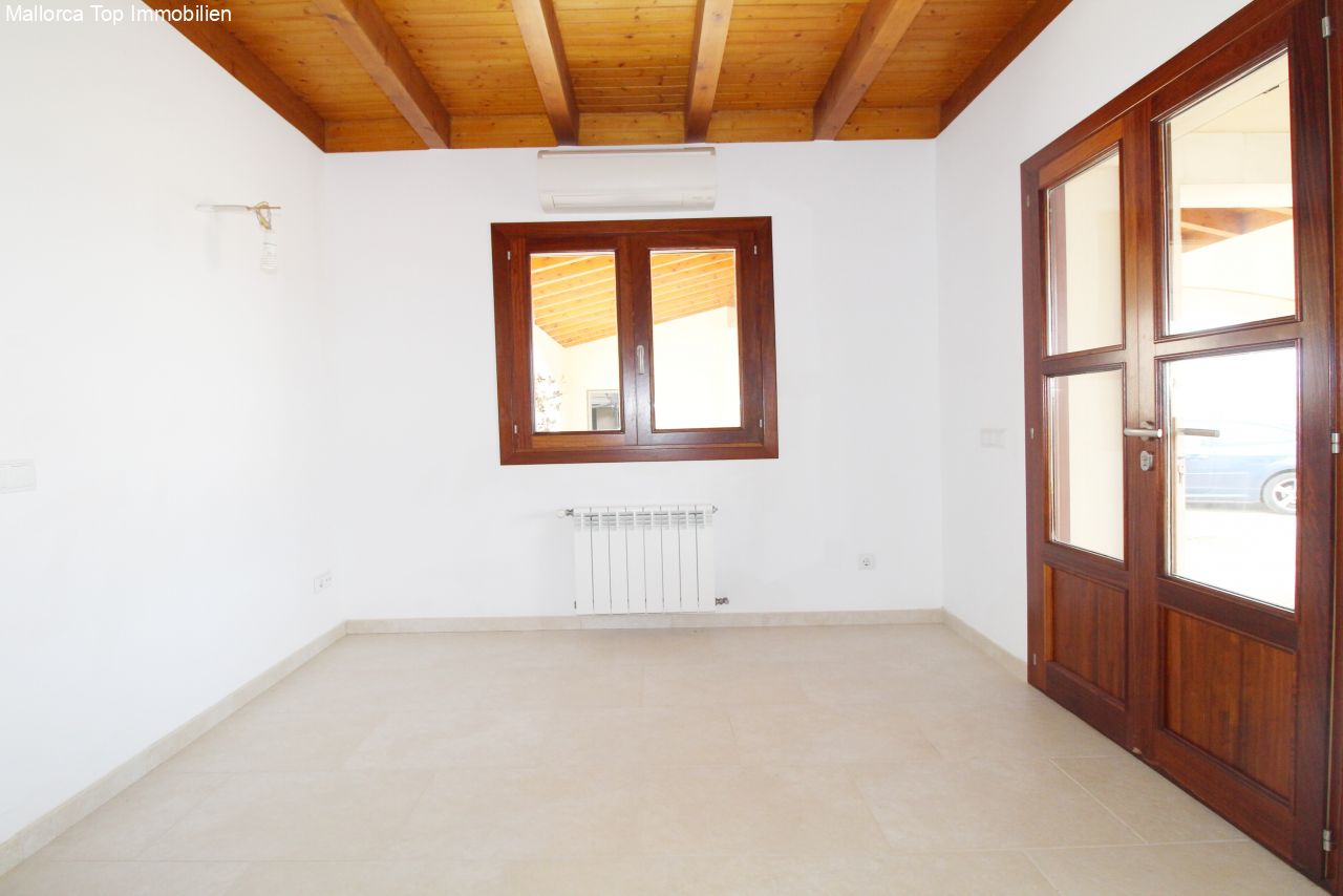 Bright room with wooden beam ceiling, fireplace, and direct access to the terrace.