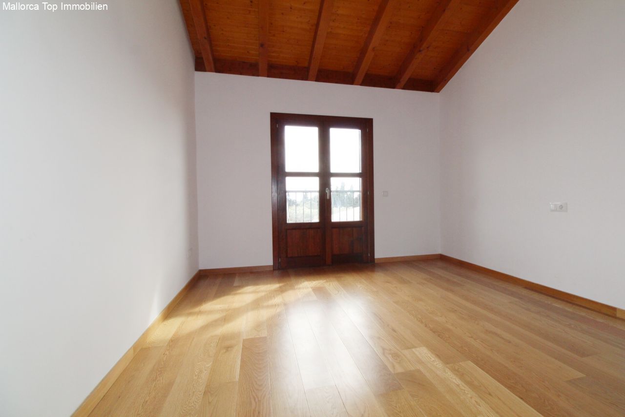 Bright room with rustic wooden beam ceiling and French glass doors to the balcony