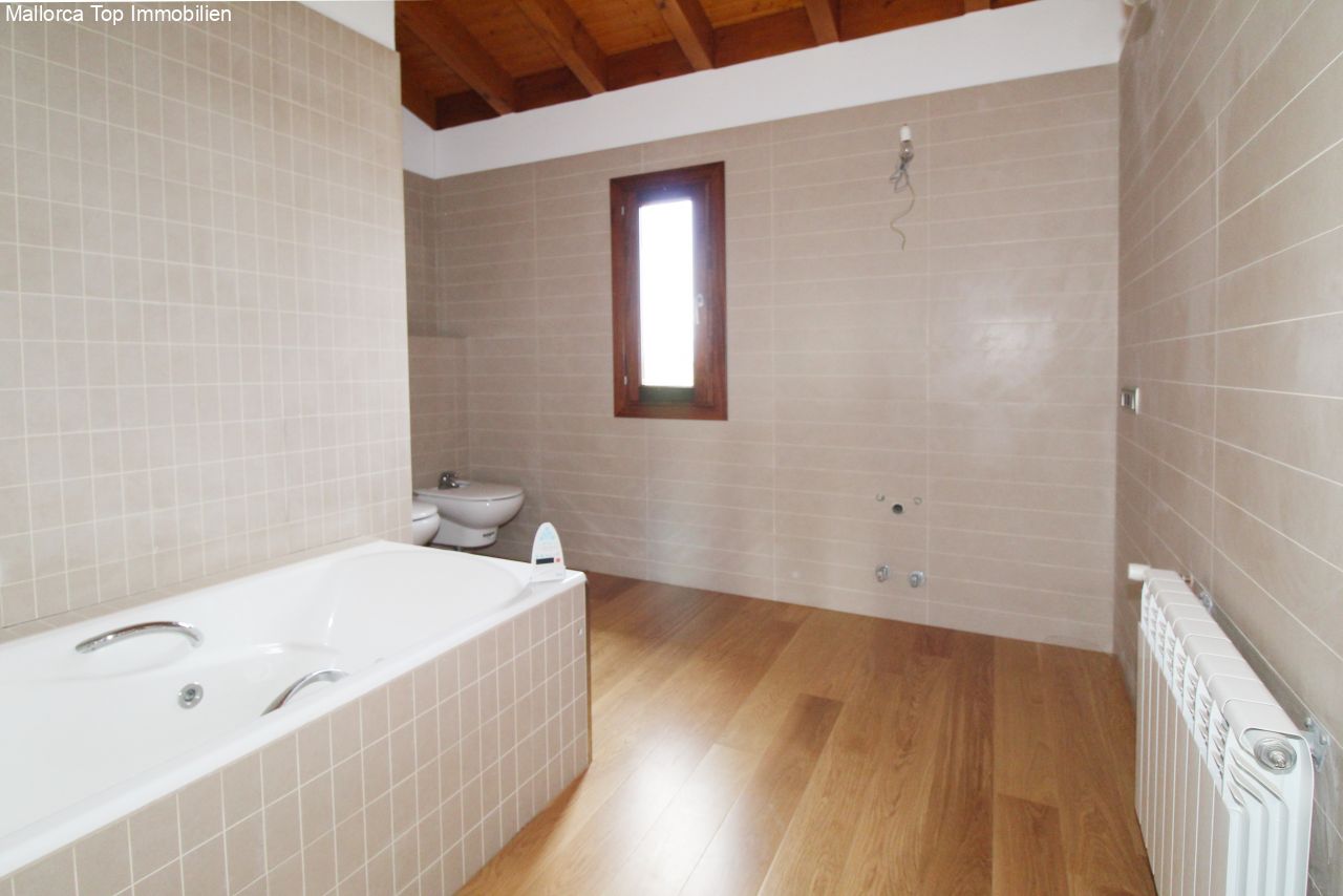 Bathroom with bathtub, separate toilet, and natural light from skylight