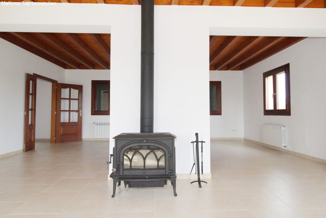 Open living area with a characterful wooden beam ceiling and central fireplace.