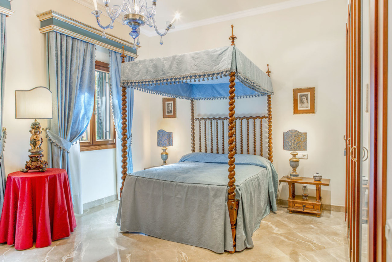 Majestic bedroom with four-poster bed and chandelier – elegant room proportions with stylish glass doors to the outdoor area Majestic bedroom with four-poster bed and chandelier – elegant room proportions with stylish glass doors to the outdoor area