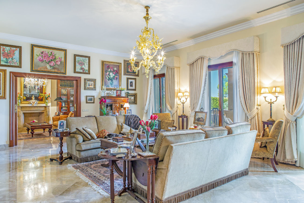 Elegant living room with crystal chandelier and fireplace area – open layout with elegant glass doors to the outdoor area Elegant living room with crystal chandelier and fireplace area – open layout with elegant glass doors to the outdoor area
