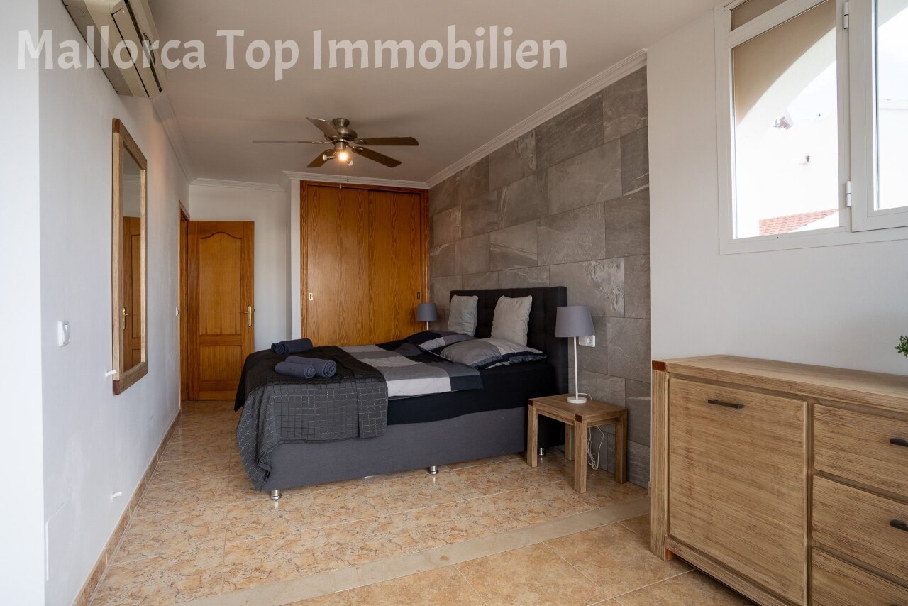 Spacious bedroom with stone accent wall and practical ceiling fan installation
