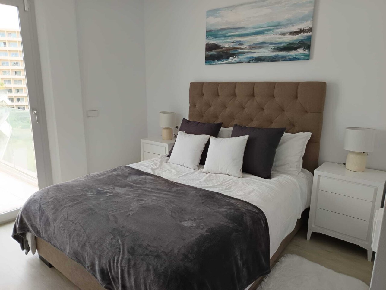 Bright bedroom with a large headboard and direct window view Bright bedroom with a large headboard and direct window view