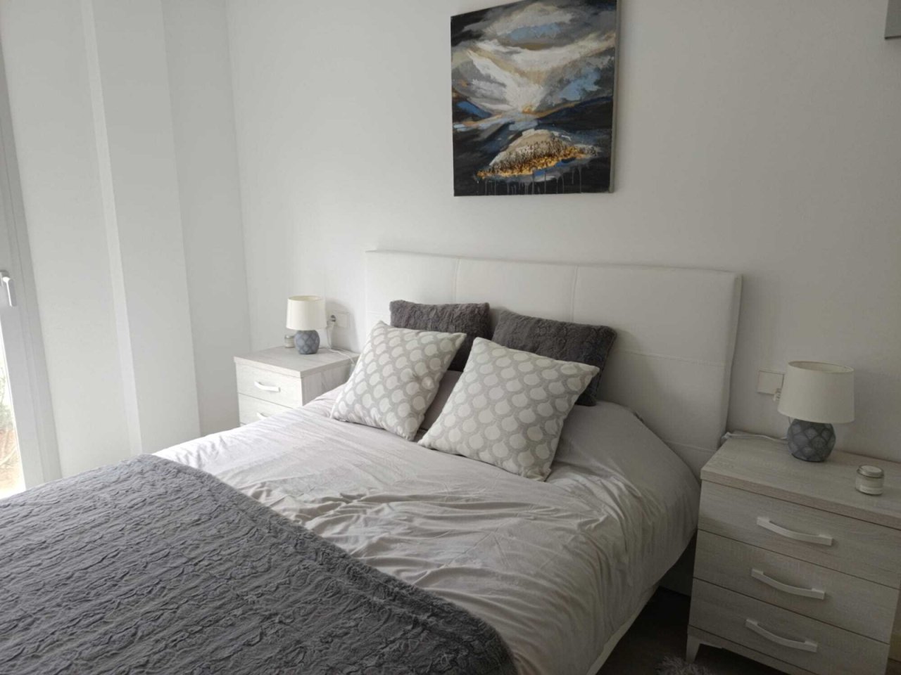 Bright bedroom with floor-to-ceiling headboard and integrated nightstand function Bright bedroom with floor-to-ceiling headboard and integrated nightstand function