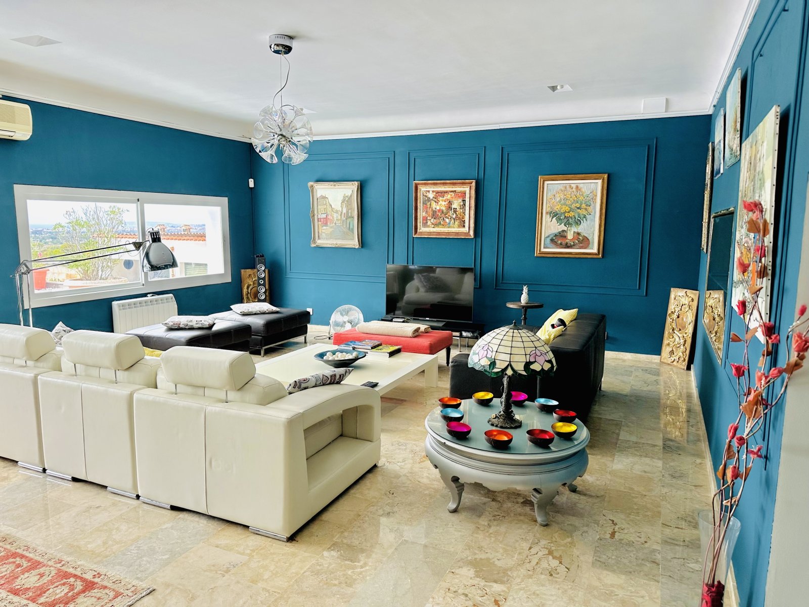 Living area with high ceiling design and large window front offering panoramic view