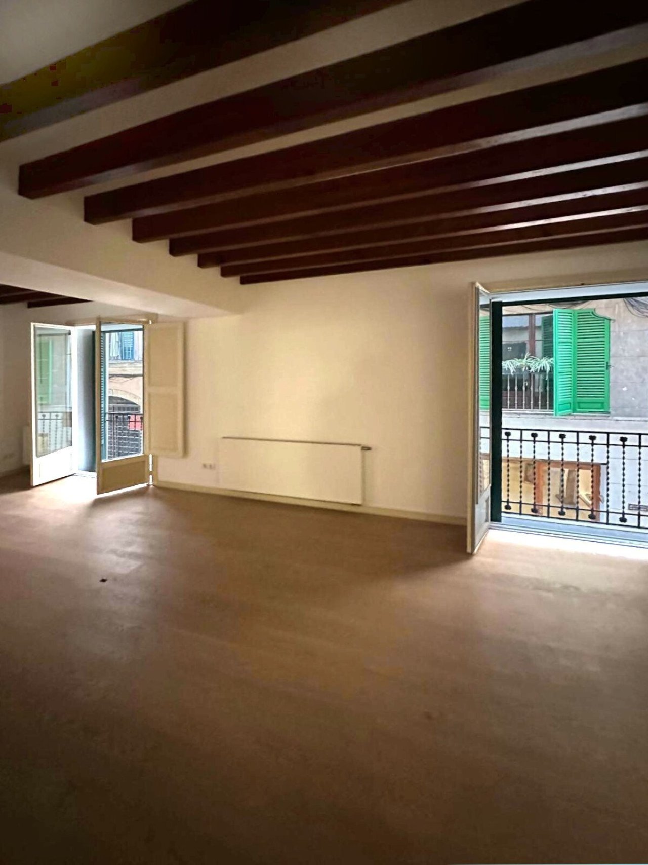 Bright living space with double balcony access and striking ceiling beams