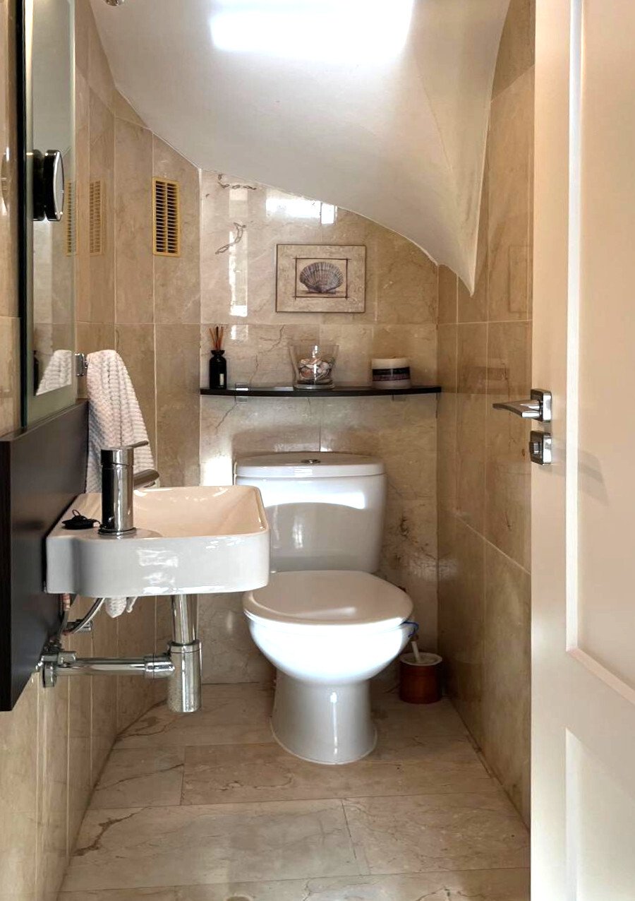 Elegant guest bathroom with high-quality marble cladding and optimal lighting through skylights Elegant guest bathroom with high-quality marble cladding and optimal lighting through skylights