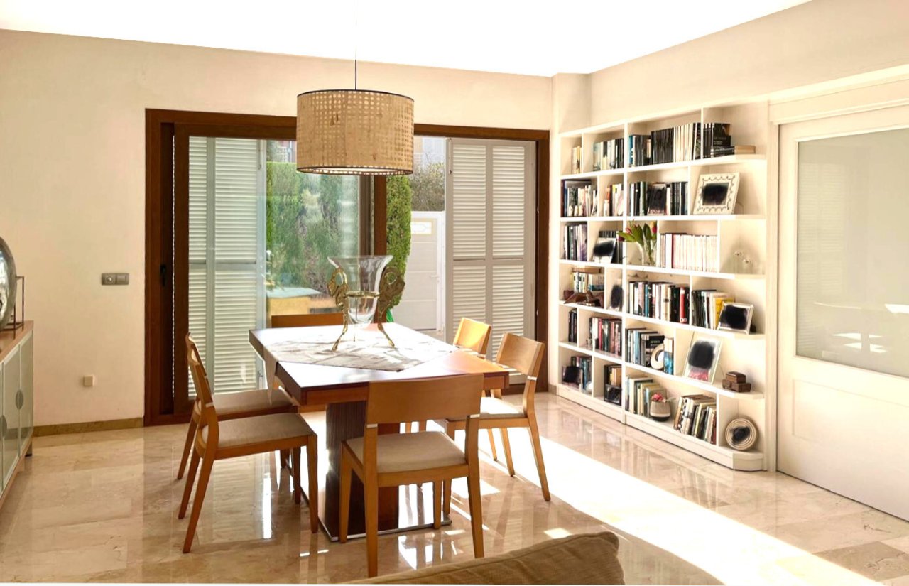 Brightly lit dining area with integrated library and access to the outdoor space Brightly lit dining area with integrated library and access to the outdoor space