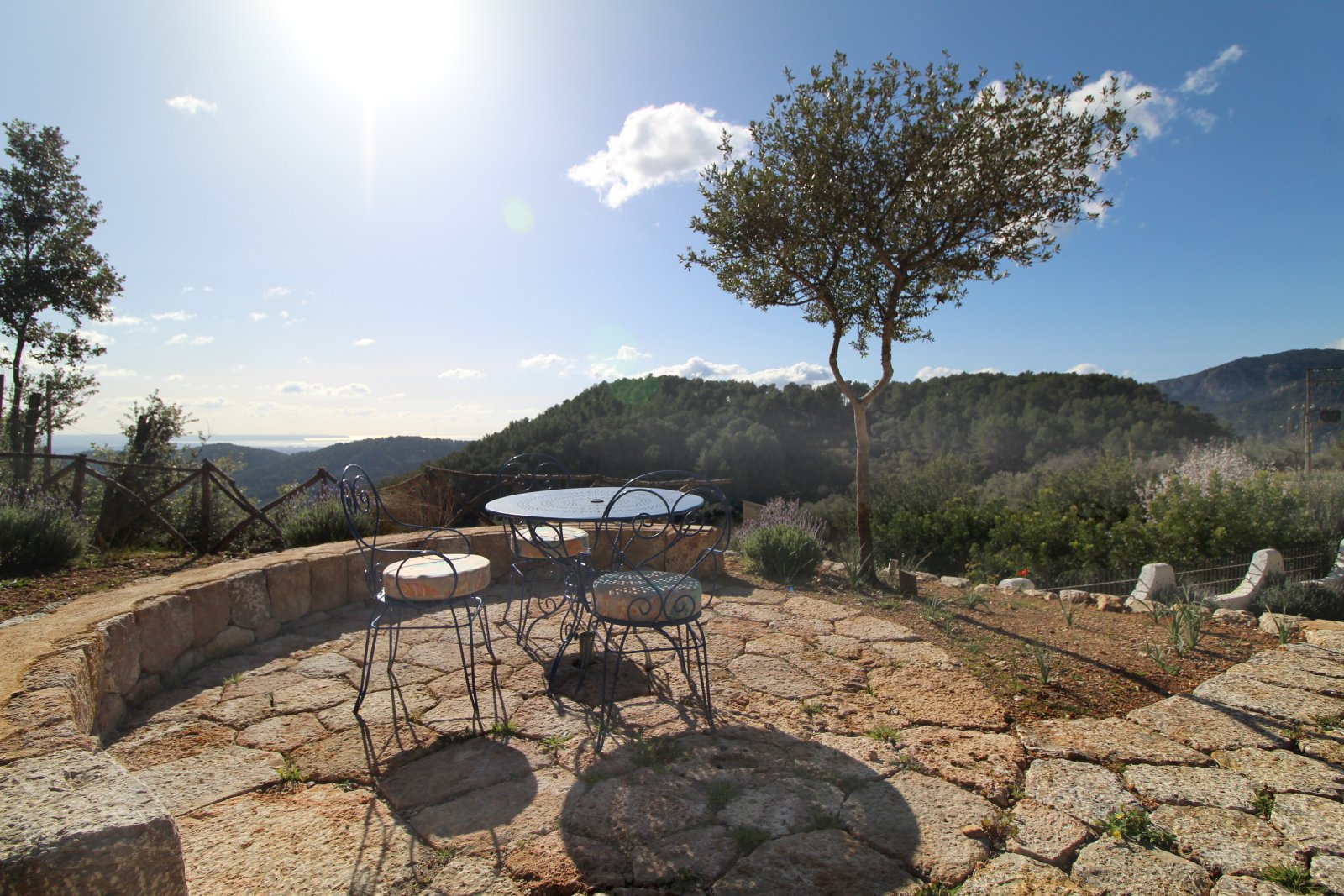 Terrace space with natural stone border, pergola structure, and open view over the hilly landscape