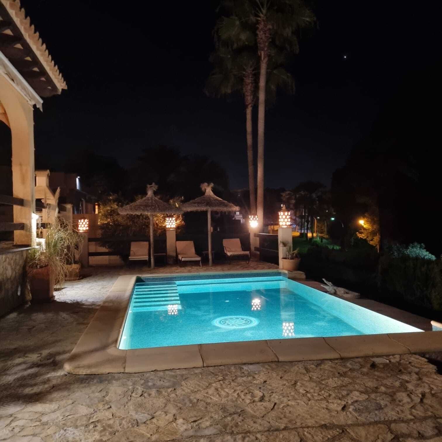 Illuminated pool area with elegant terrace design and comfortable lounge zone Illuminated pool area with elegant terrace design and comfortable lounge zone
