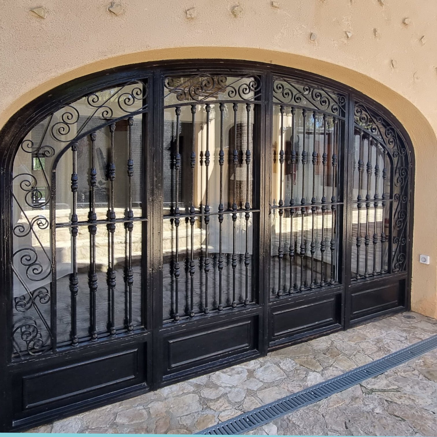 Elegant entrance gate with wrought iron craftsmanship and a distinctive rounded arch frame Elegant entrance gate with wrought iron craftsmanship and a distinctive rounded arch frame