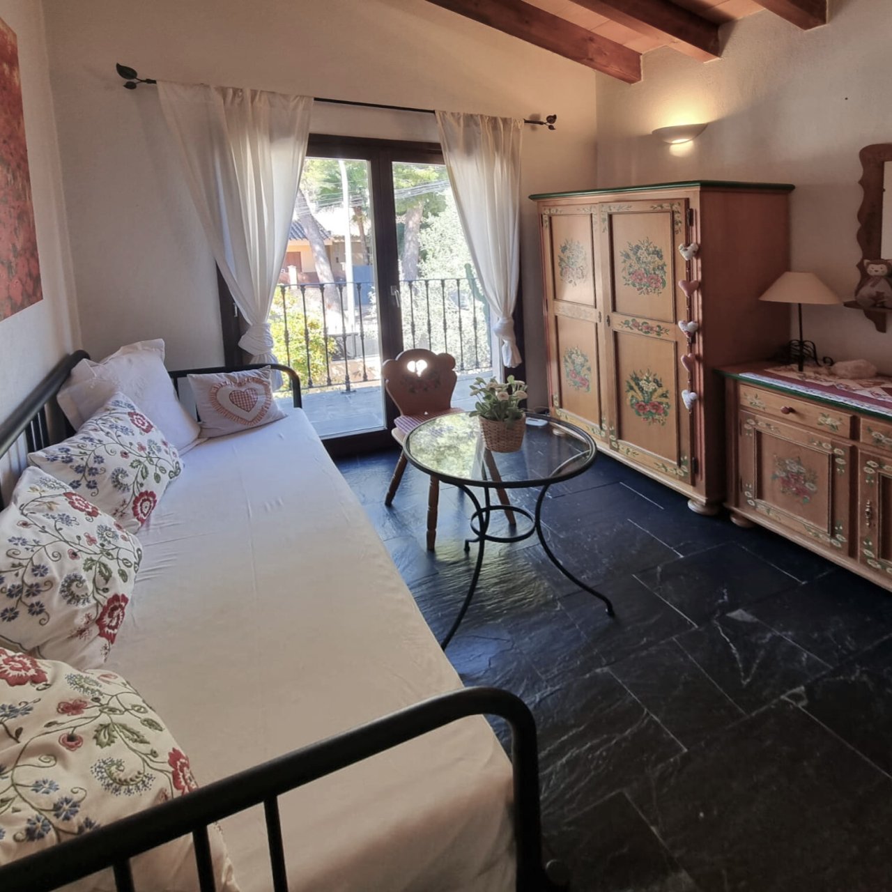 Charming guest room with balcony access, wooden beam ceiling, and thoughtful layout Charming guest room with balcony access, wooden beam ceiling, and thoughtful layout