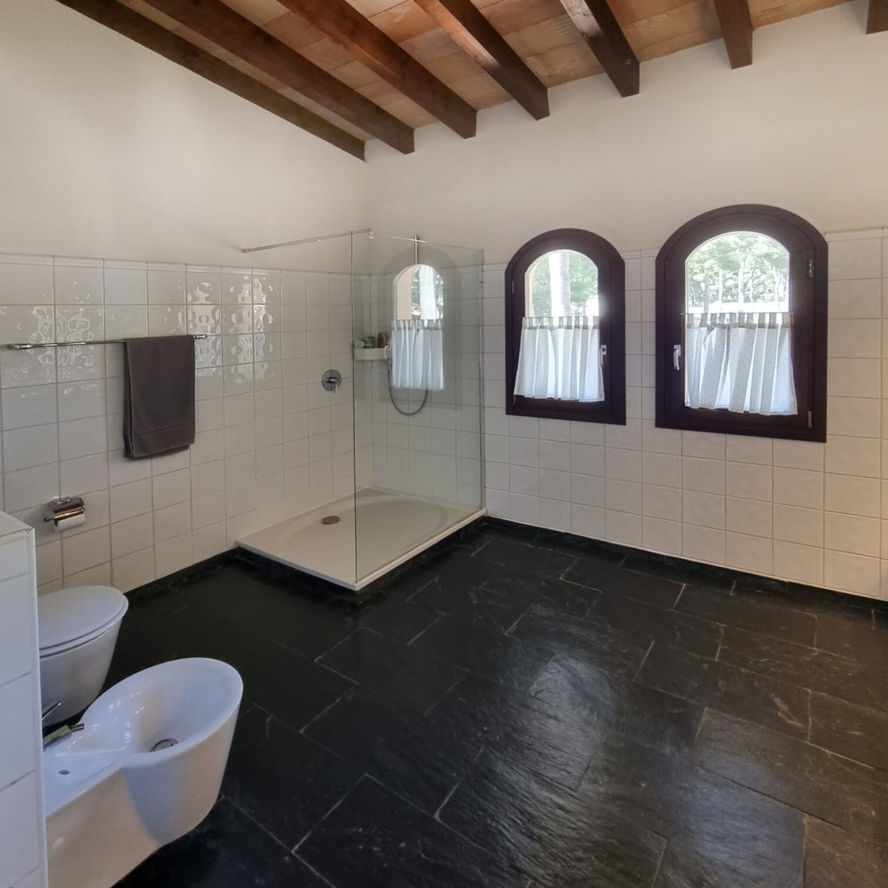 Luxurious bathroom with a walk-in glass shower, double vanity, and distinctive sash windows. Luxurious bathroom with a walk-in glass shower, double vanity, and distinctive sash windows.