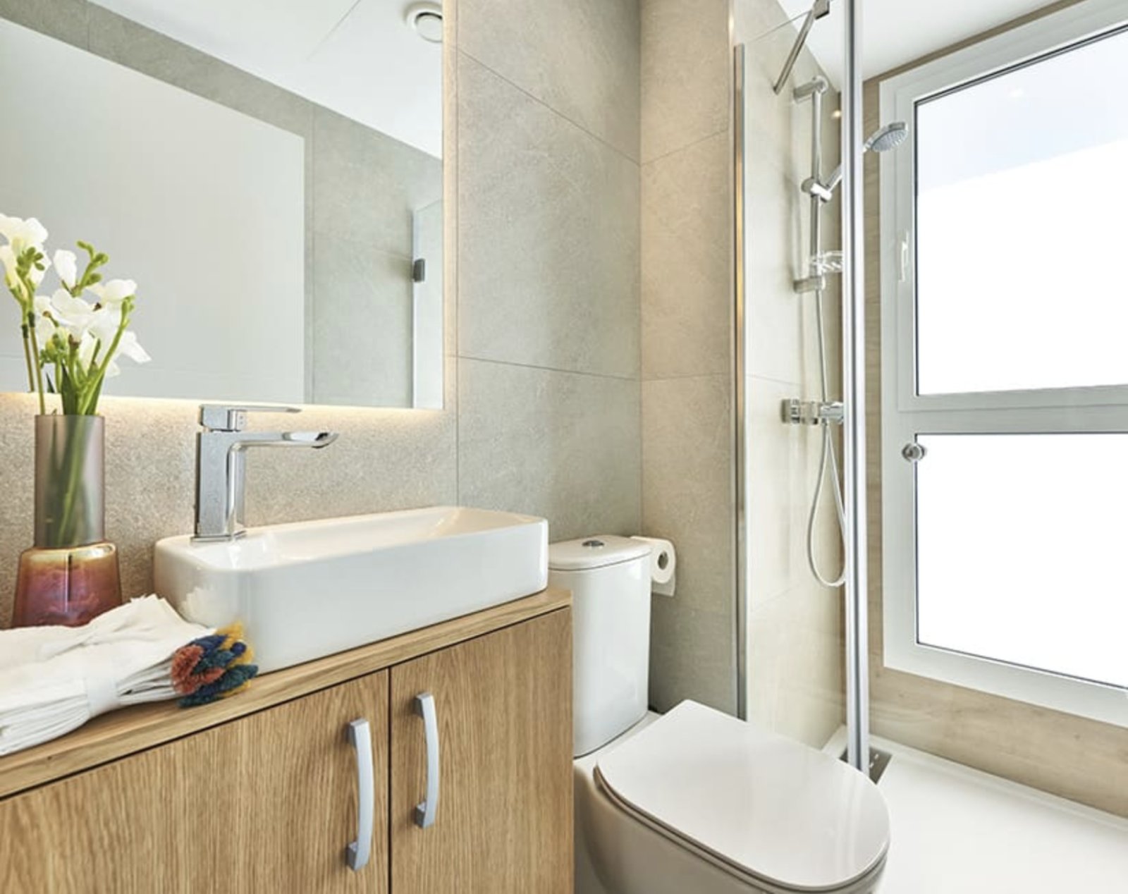 Modern bathroom with walk-in shower and illuminated mirror wall