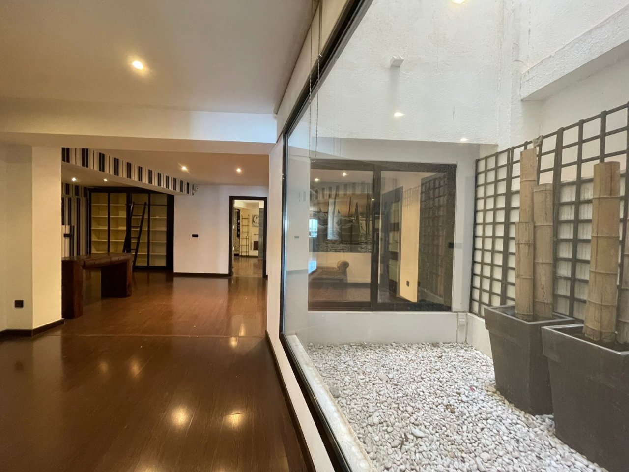 Área de estar con transiciones fluidas al patio interior privado y arquitectura moderna de vidrio