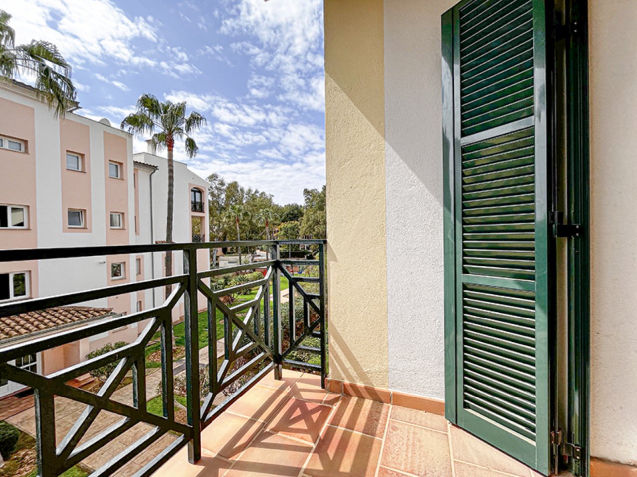 Terraza soleada con elegante mobiliario para balcón y persiana verde