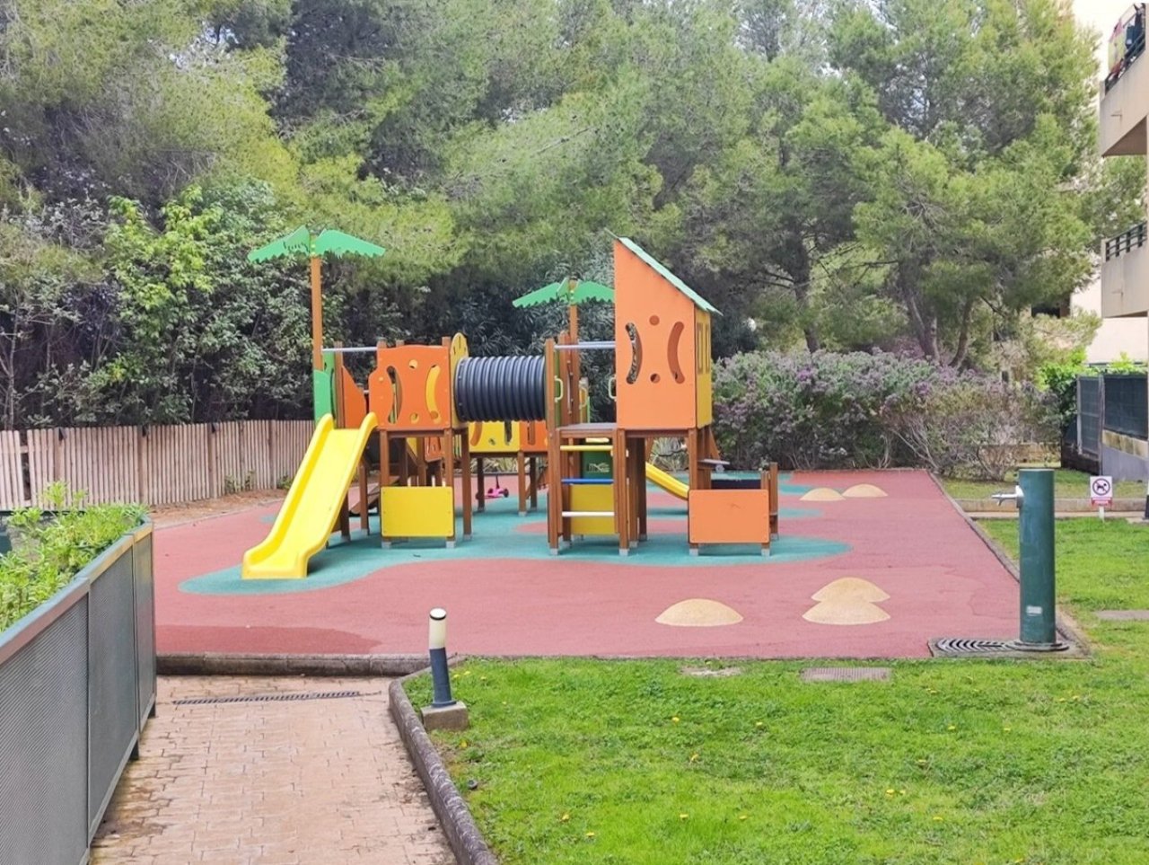 Parque infantil moderno con tobogán, elementos de escalada y superficie de protección contra golpes