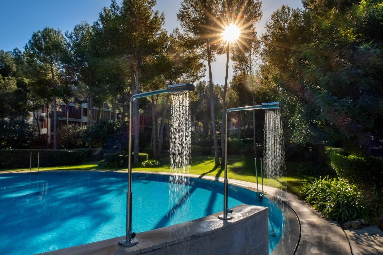 Zona de refresco con duchas exteriores modernas y un ambiente similar a un parque Zona de refresco con duchas exteriores modernas y un ambiente similar a un parque