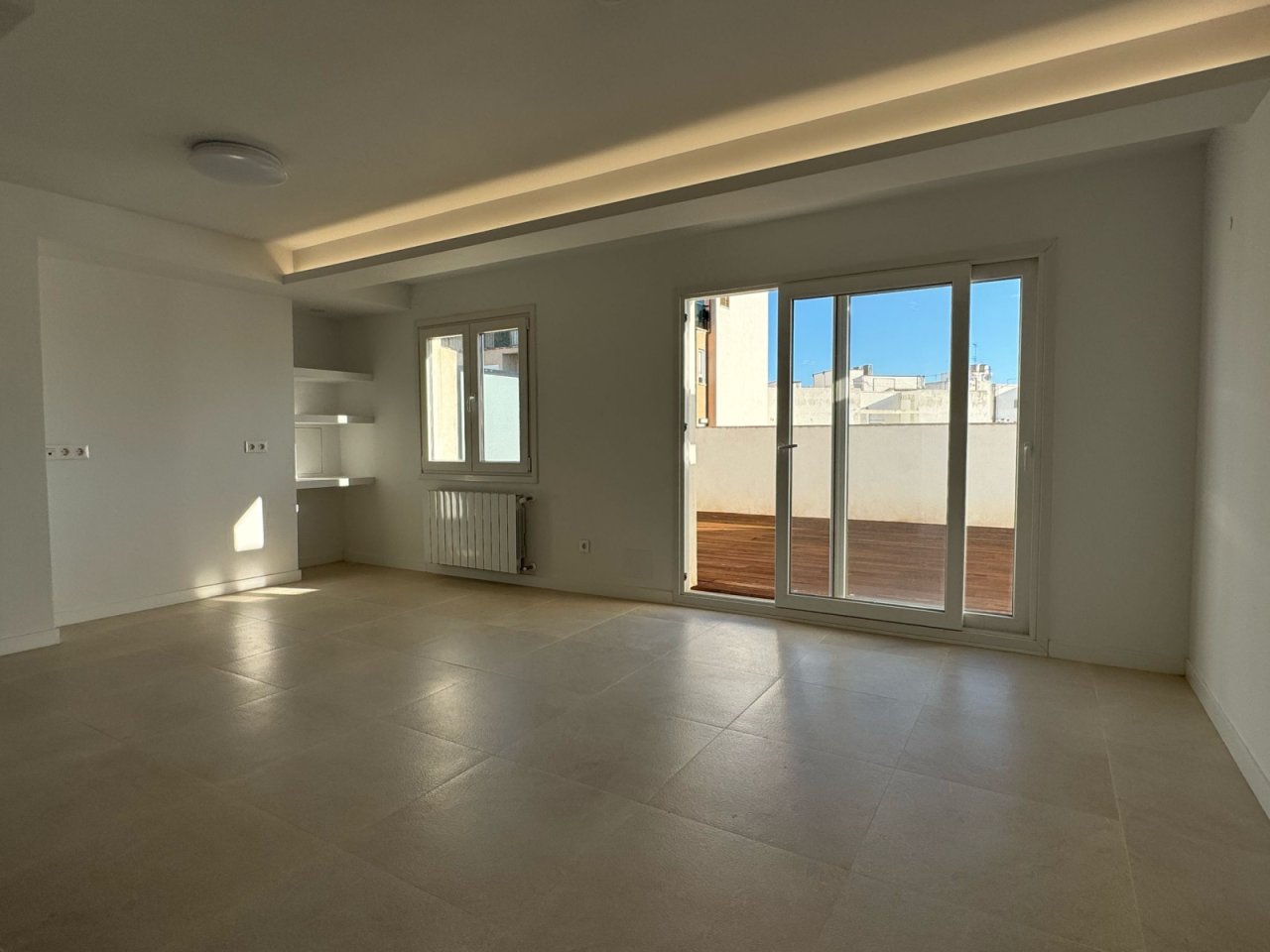 Sala luminosa con acceso directo a la terraza y diseño moderno del techo