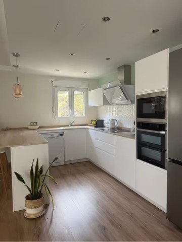 Cocina moderna con forma en L práctica y electrodomésticos empotrados de alta calidad Cocina moderna con forma en L práctica y electrodomésticos empotrados de alta calidad