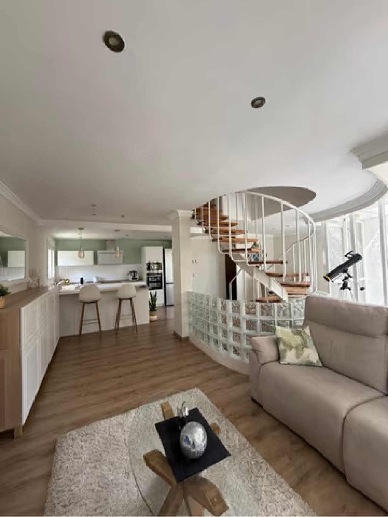 Amplia zona de estar abierta con una elegante escalera de caracol y una moderna cocina en línea Amplia zona de estar abierta con una elegante escalera de caracol y una moderna cocina en línea