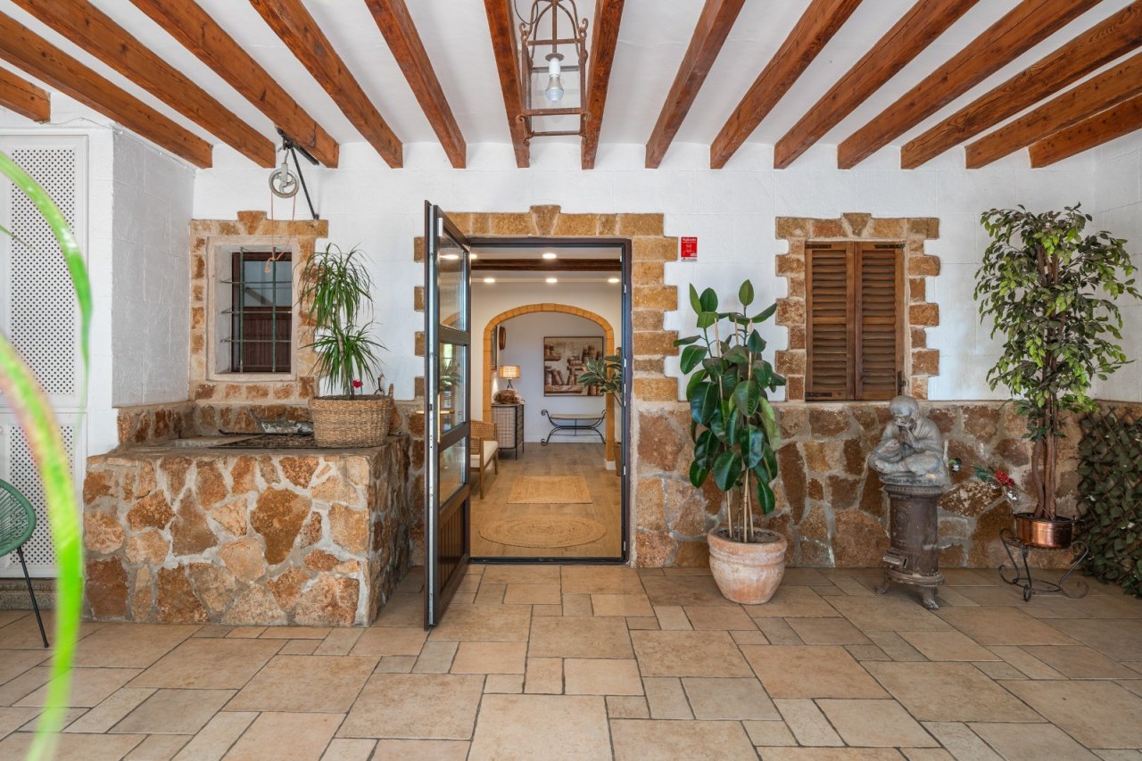 Entrada con carácter con muros de piedra natural maciza, techo de vigas de madera y elegidos arcos de piedra
