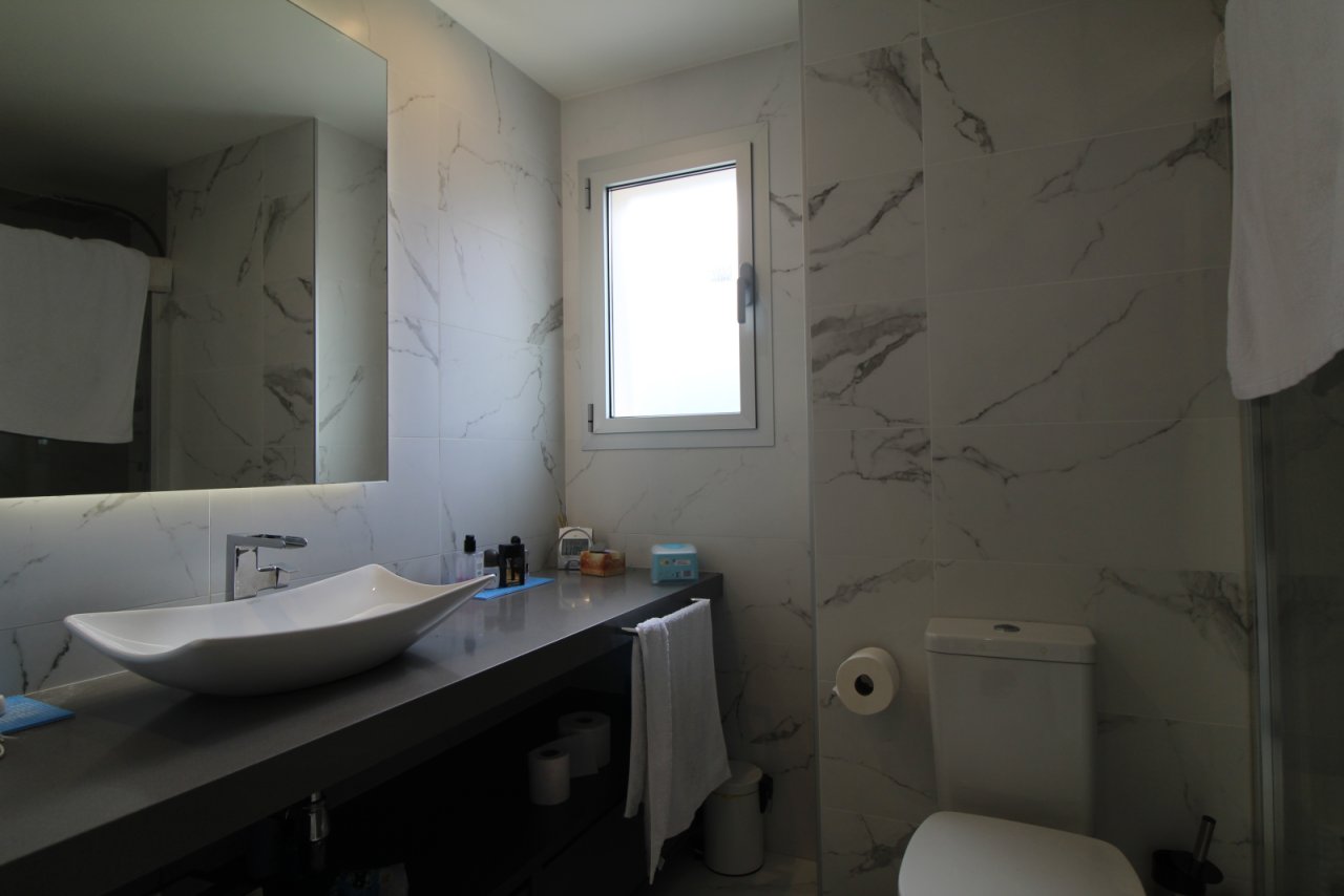 Baño moderno para invitados con aspecto de mármol y ducha a nivel del suelo