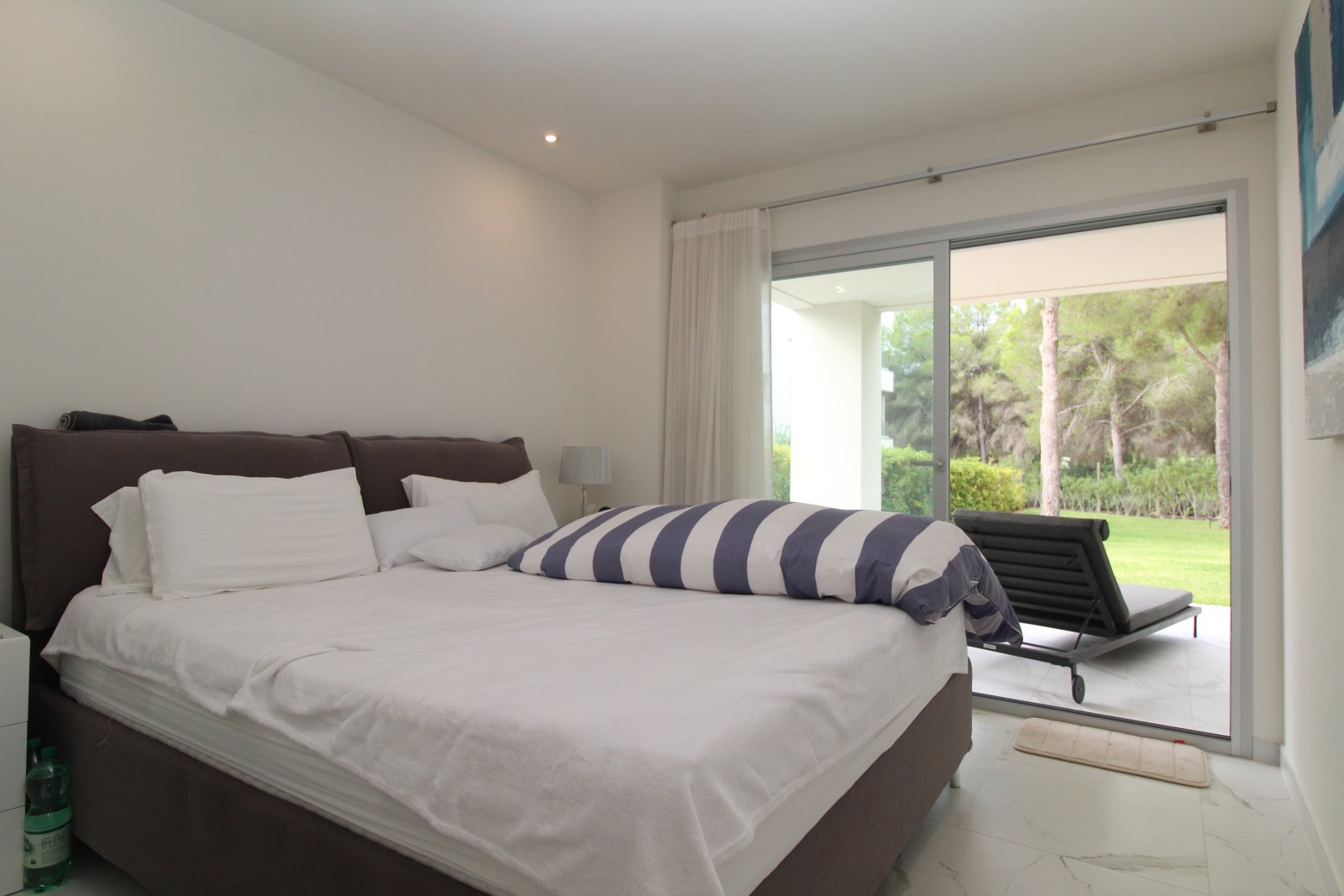 Dormitorio principal con elementos correderos de altura completa y vistas al jardín