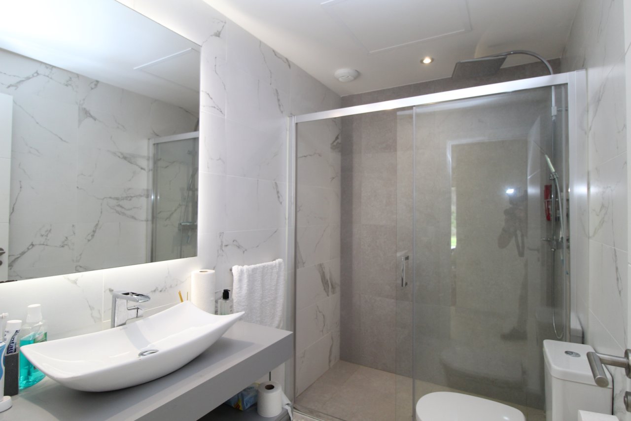 Baño elegante con ducha a ras y espejo con iluminación