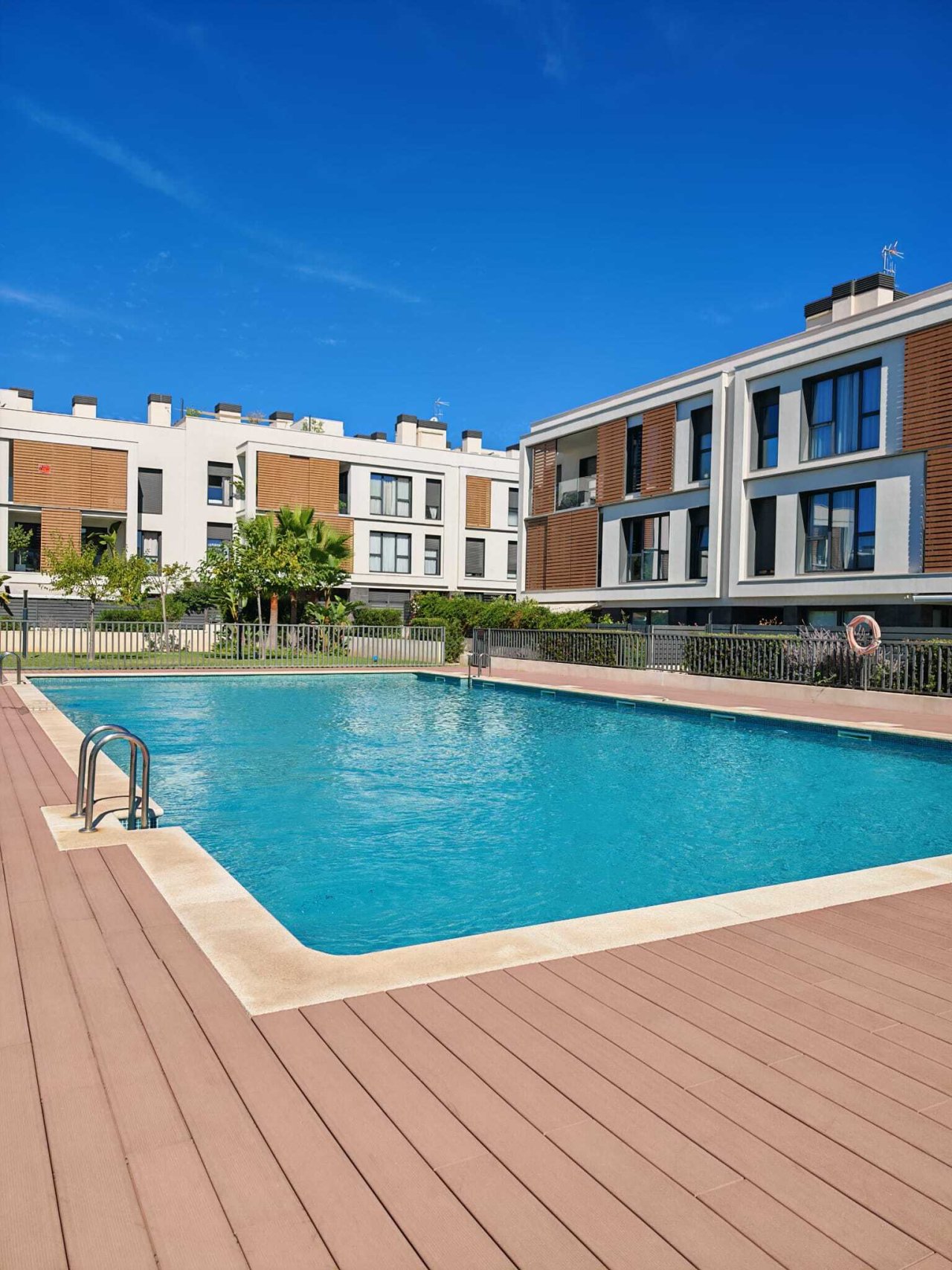 Piscina comunitaria con amplias zonas de descanso y complejo residencial moderno Piscina comunitaria con amplias zonas de descanso y complejo residencial moderno