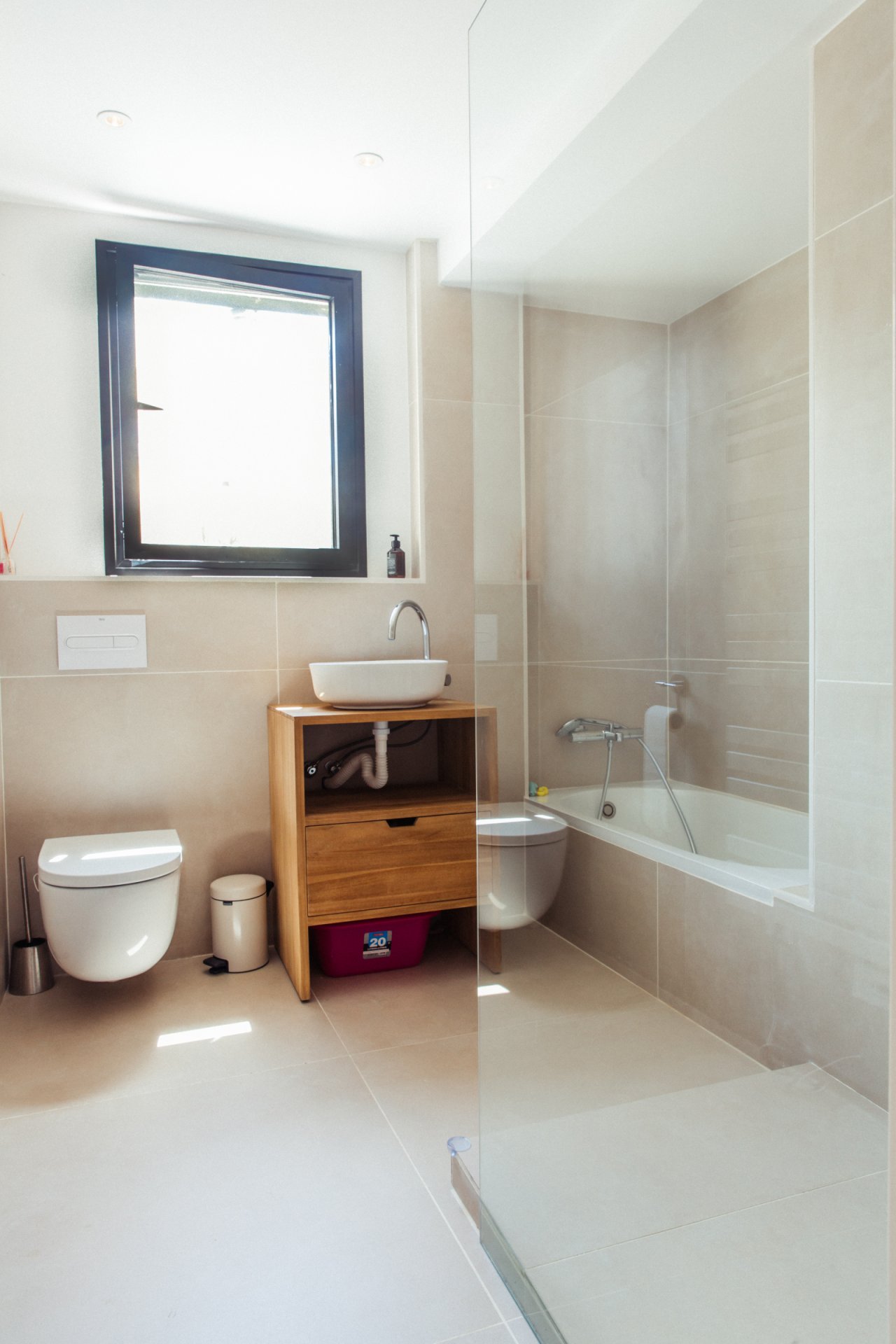 Baño moderno con bañera independiente, iluminación natural por ventana y distribución práctica de la zona húmeda