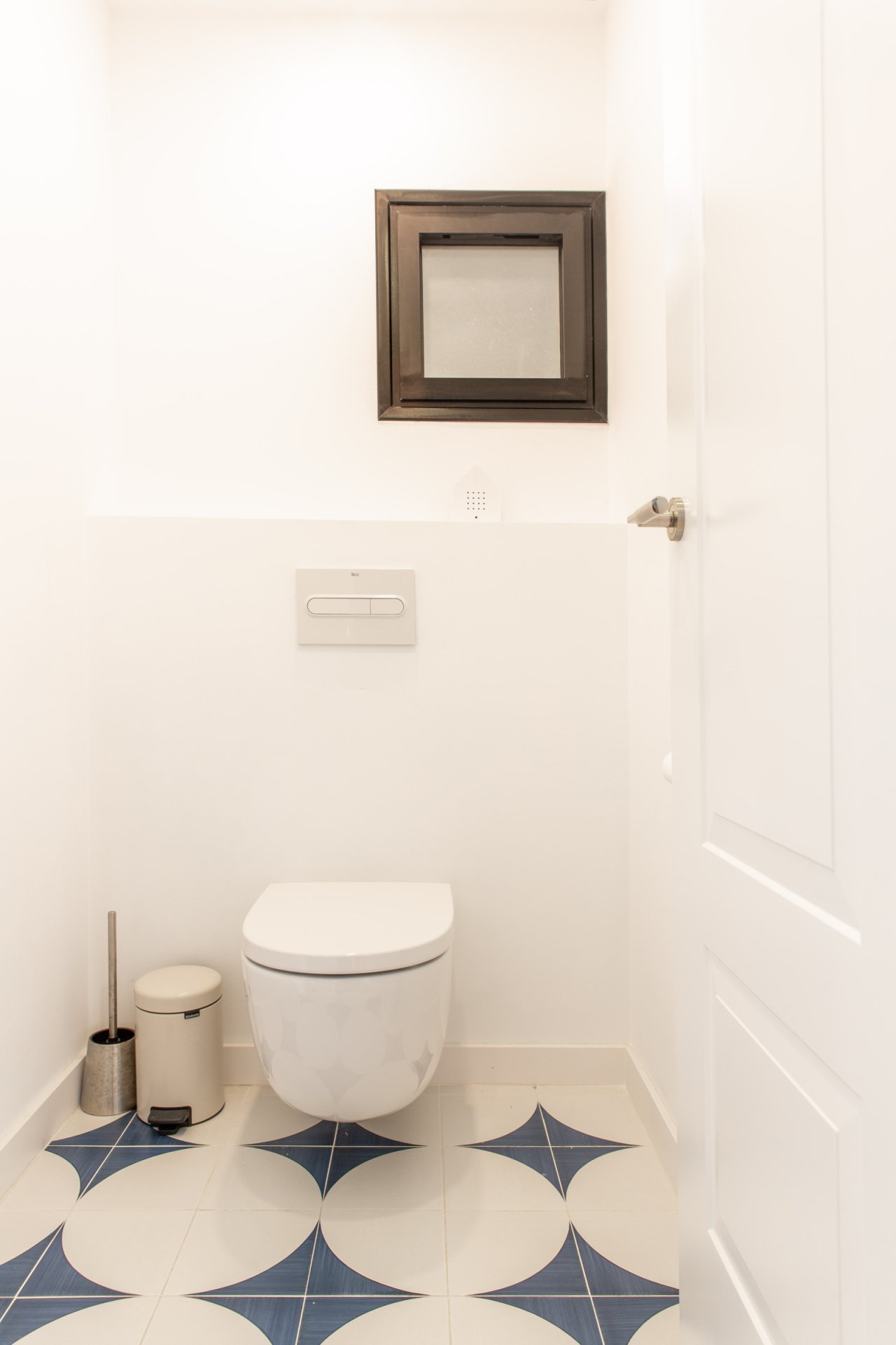 Baño de invitados moderno con instalaciones integradas en la pared y sistema de lavado de alta calidad