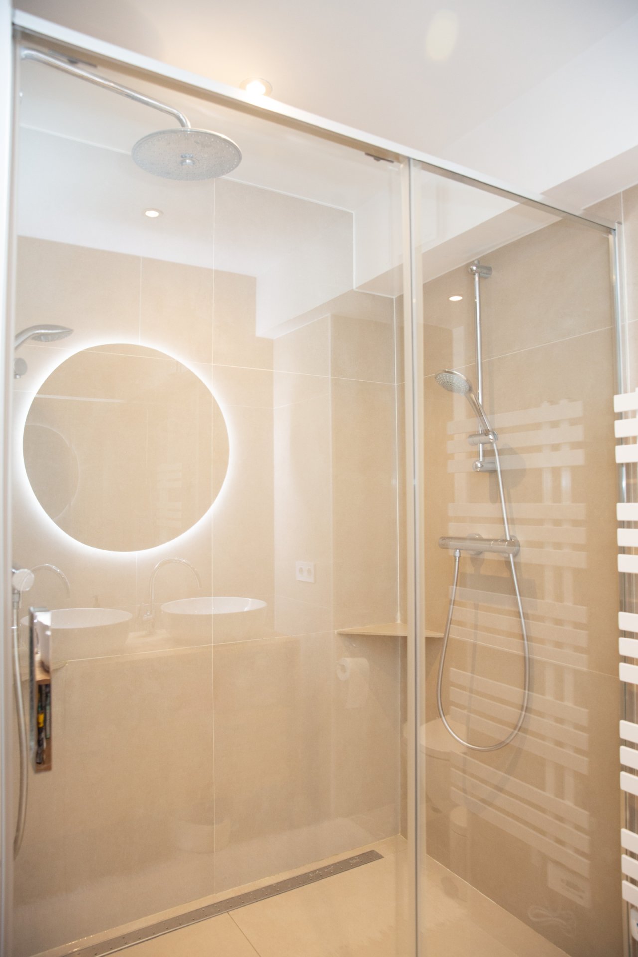 Baño moderno con ducha a ras de suelo, doble lavabo y sistema de espejo LED