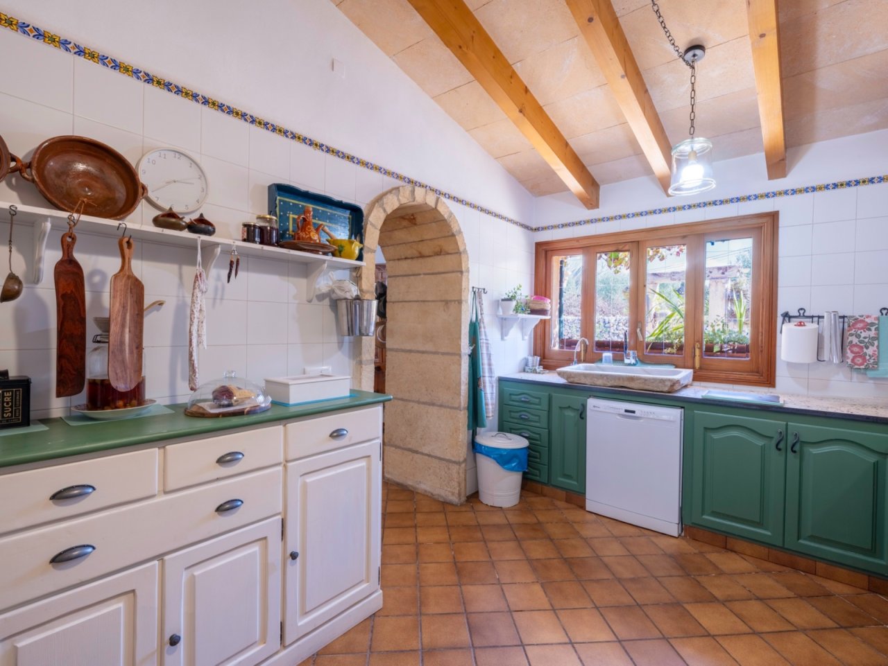 Cocina con arco de piedra con carácter, techo de vigas y amplias superficies de trabajo, además de acceso directo al jardín