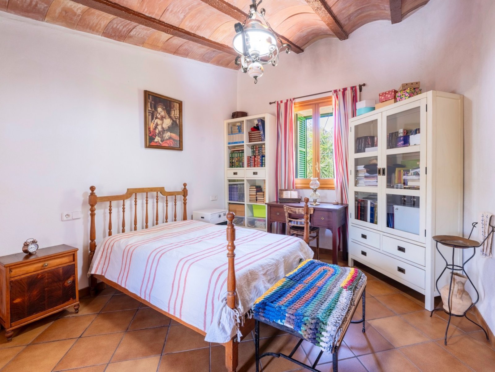 Dormitorio luminoso con vigas de madera con carácter y una amplia fachada de ventanas