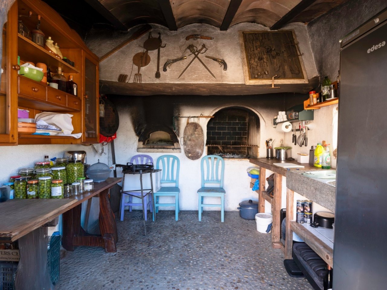 Cocina rural auténtica con arco de piedra con carácter, techo de vigas y conexión abierta con el comedor